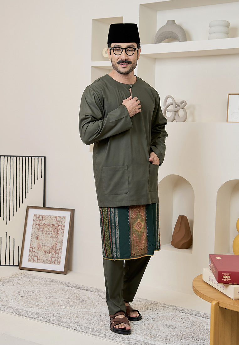 Man wearing a sage green traditional baju melayu teluk belanga outfit in a modern interior setting