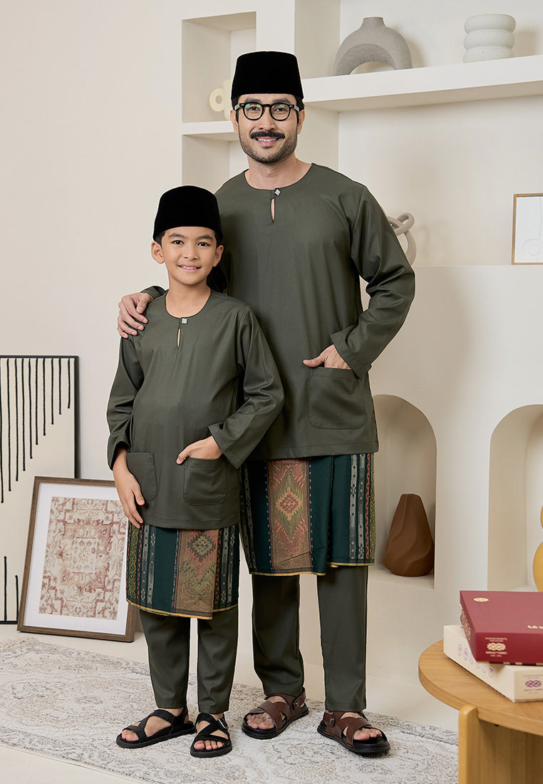 Father and son wearing matching traditional baju melayu teluk belanga with an olive-green outfit in a home setting
