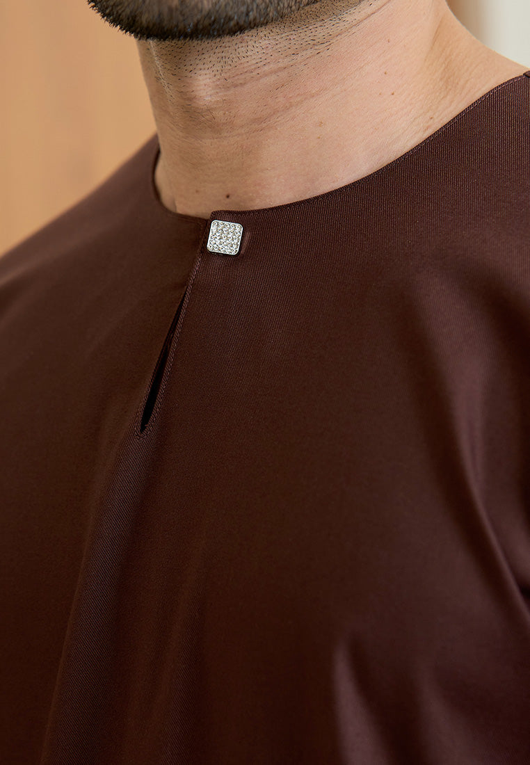 Close-up of a person wearing a rich brown traditional baju melayu teluk belanga with a decorative magnetic button.